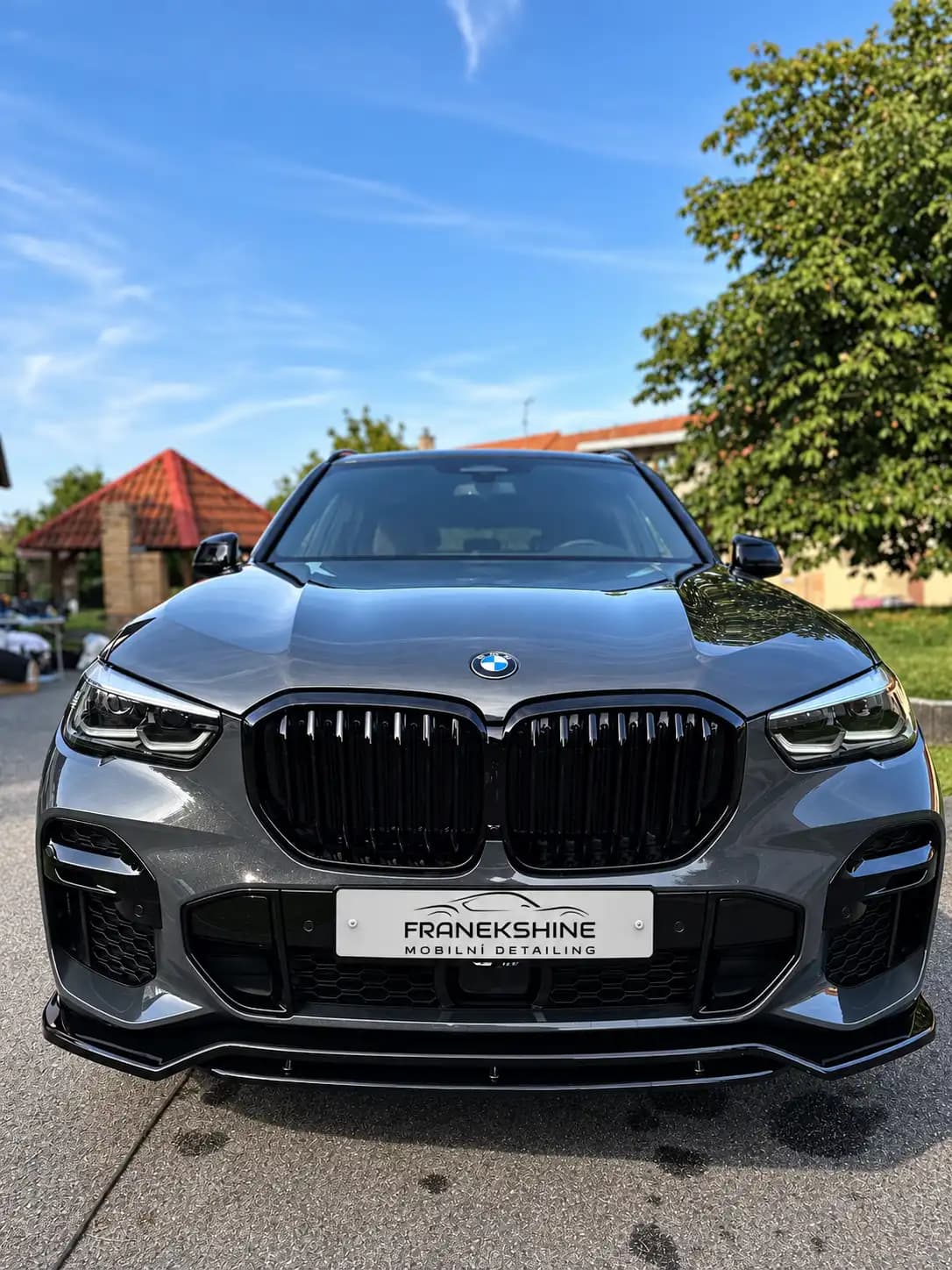 Naleštěné šedé BMW X5 s čistým lakem a jasnou oblohou